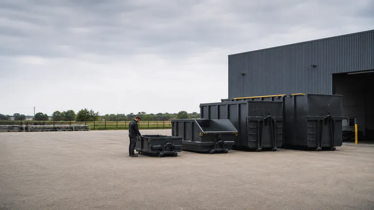 Plusieurs volumes de bennes alignés avec un technicien pour donner l’échelle.